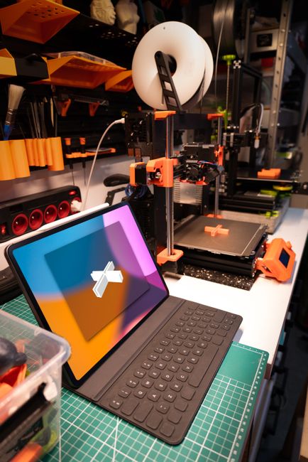 A modern workspace featuring a 3D printer and tablet for creative technology projects.